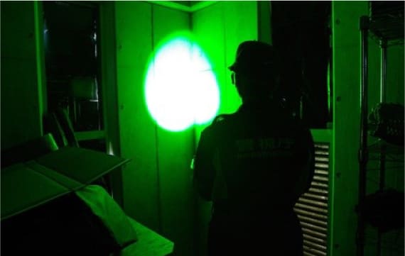 図2：肉眼では判別できない潜在指紋の有無を高出力の緑色レーザーで探索している画像